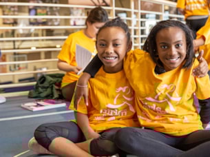 Two Girls on the Run participants in yellow shirts run while smiling at the camera Two Girls on the Run participants in yellow shirts run while smiling at the camera